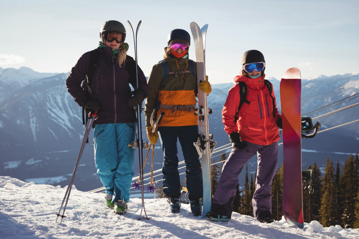 Three skiers with skies standing on snowy landscape in ski resort